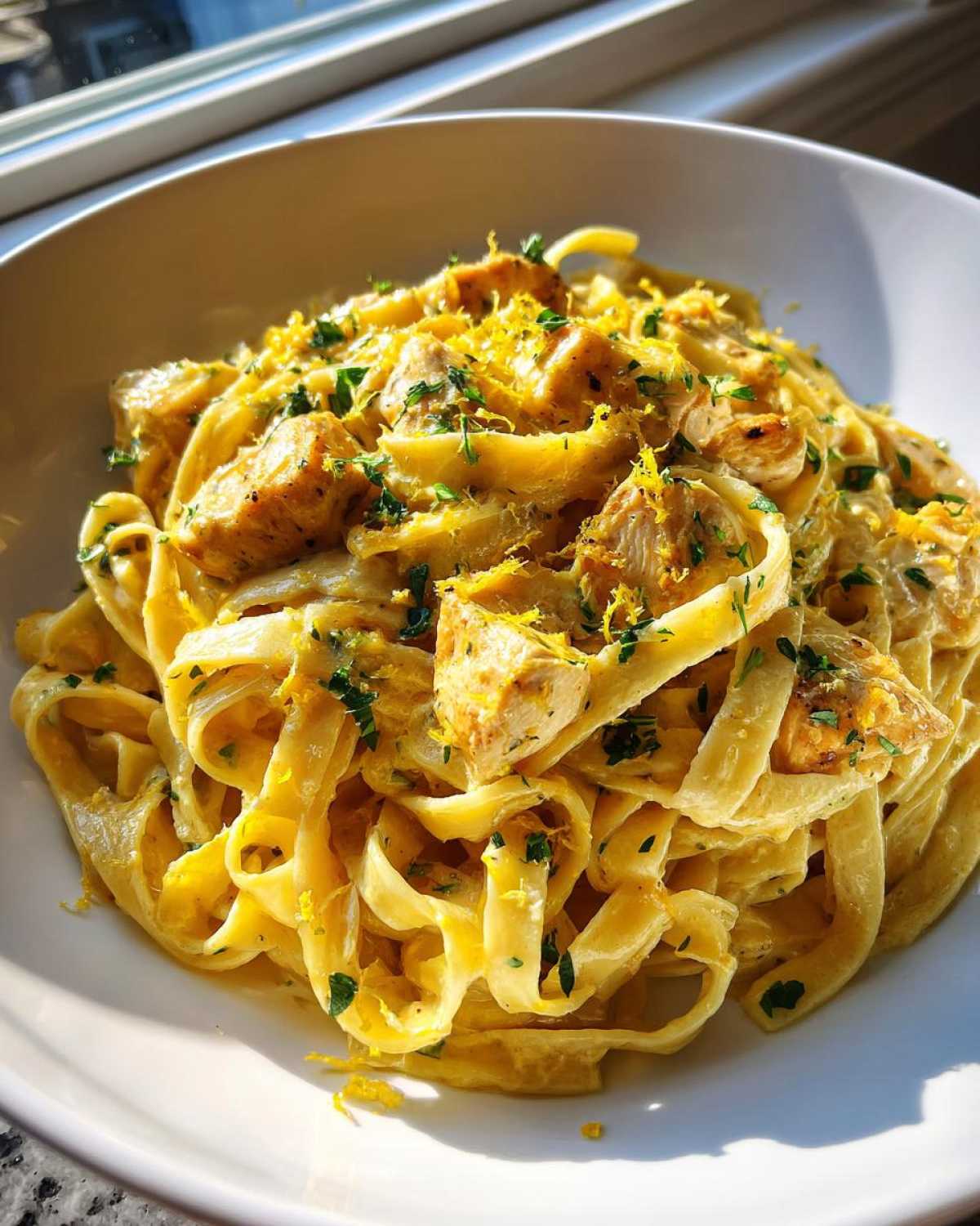 Close-up of Creamy Lemon Garlic Pasta with Chicken, topped with lemon zest and parsley.