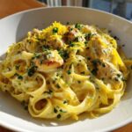 Close-up of a bowl of Creamy Lemon Garlic Pasta with Chicken, topped with lemon zest and parsley.