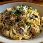 A close-up of a bowl of Creamy Mushroom Chicken Pasta with Parmesan, topped with fresh parsley.