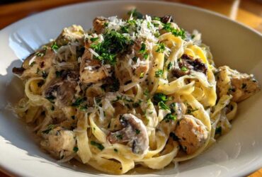 A close-up of a bowl of Creamy Mushroom Chicken Pasta with Parmesan, topped with fresh parsley.