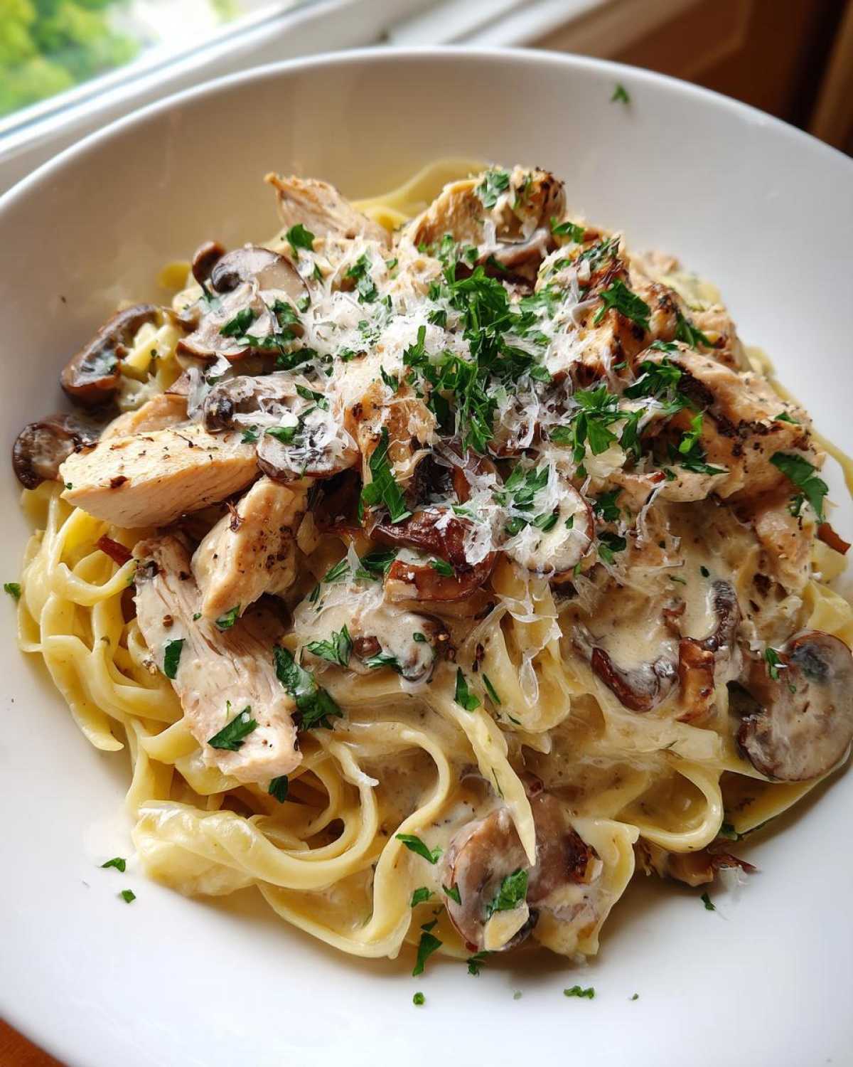 A close-up of Creamy Mushroom Garlic Pasta with Chicken, topped with Parmesan and parsley.
