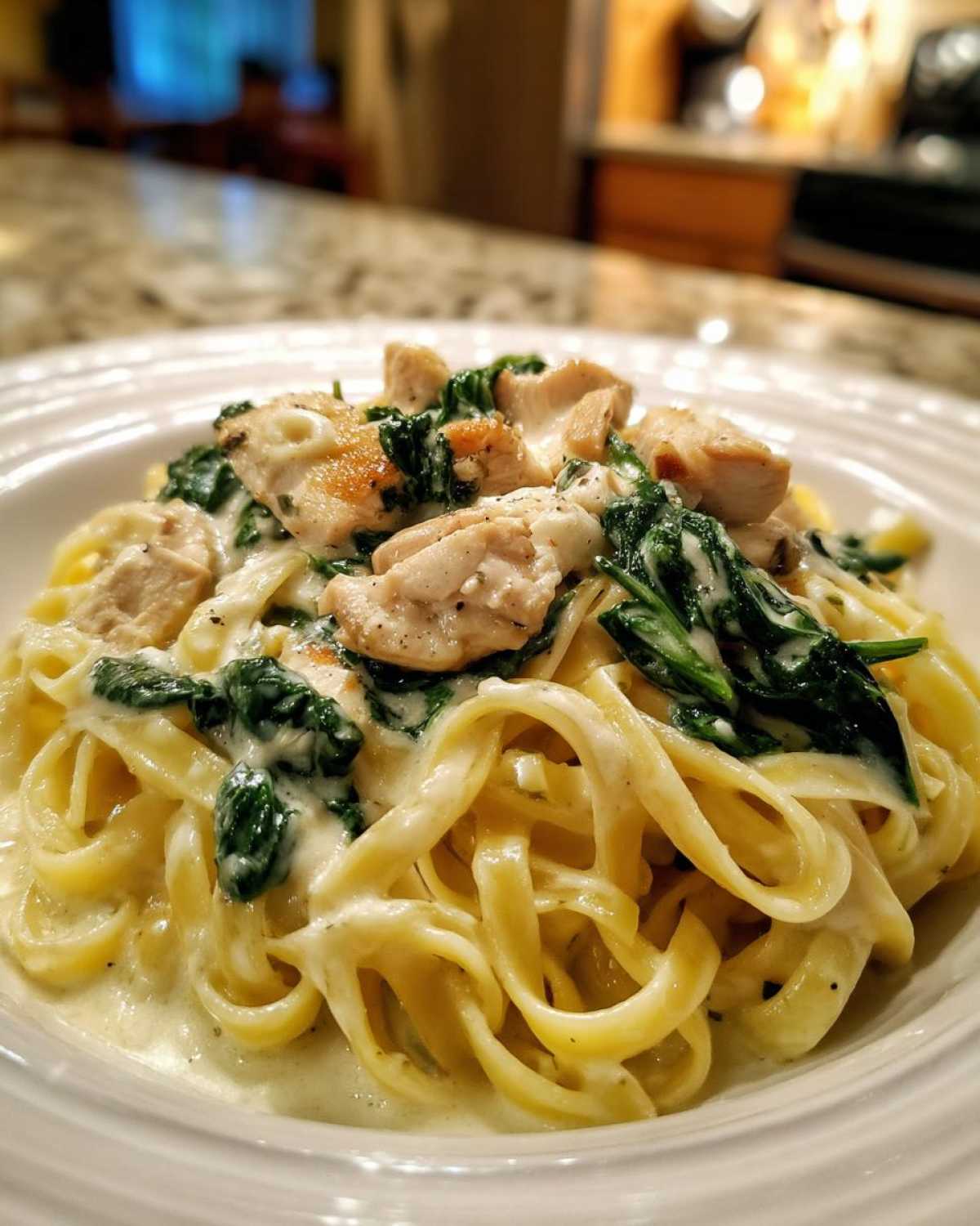 Close-up of fettuccine pasta coated in creamy sauce with chunks of chicken and wilted spinach: Creamy Spinach Alfredo Pasta with Chicken.