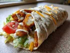 A delicious Crispy Chicken Wrap stuffed with fried chicken pieces, lettuce, tomato, cheese, and drizzled with creamy garlic sauce.