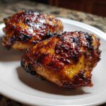 Two perfectly cooked Honey Soy Chicken Thighs with crispy, caramelized edges resting on a white plate.