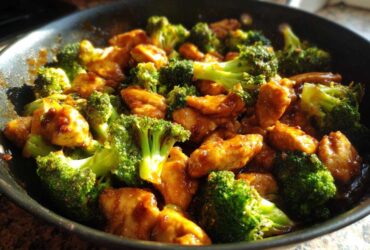 Close-up of vibrant Garlic Butter Chicken and Broccoli Stir Fry glistening in a dark skillet.