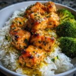 Close-up of Garlic Butter Salmon Bites glazed with sauce, served over white rice with steamed broccoli florets.