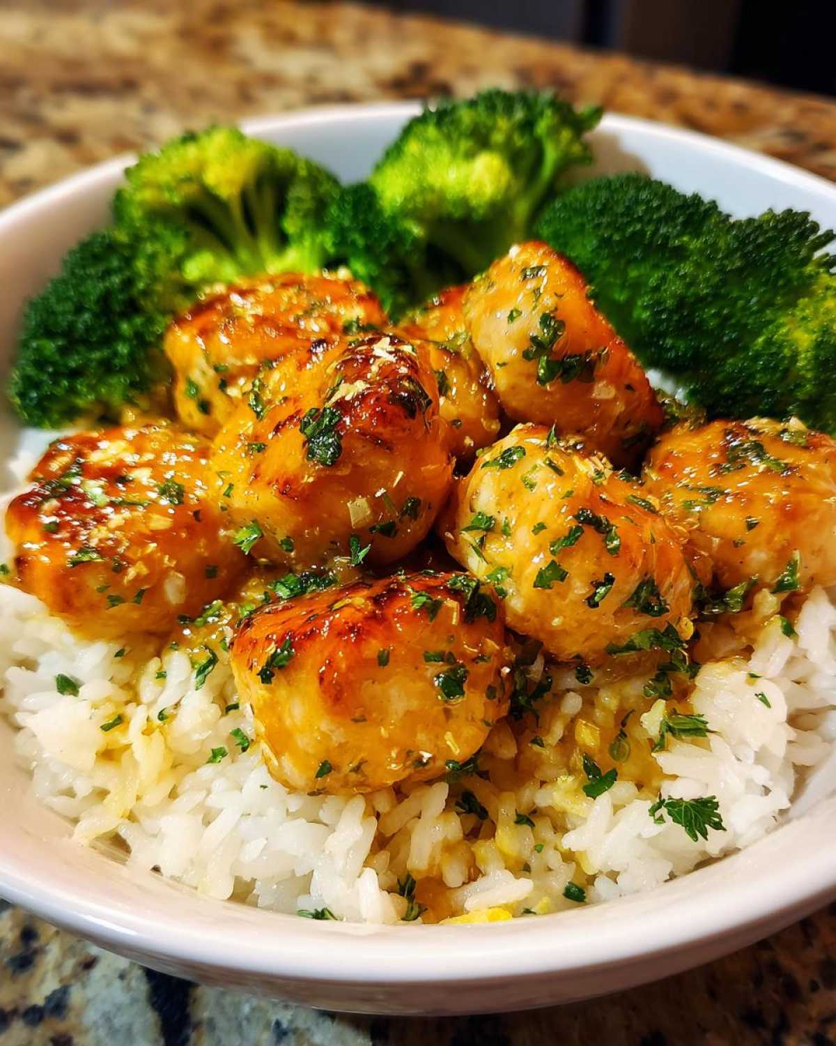 Close-up of Garlic Butter Salmon Bites served over white rice with steamed broccoli florets.