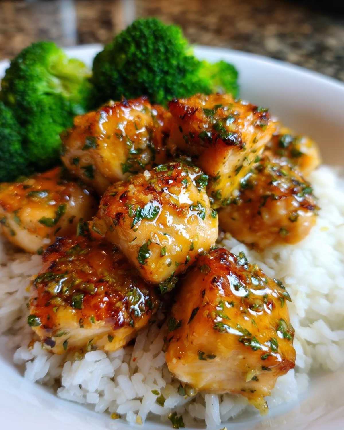 Close-up of glossy, glazed Garlic Butter Salmon Bites served over white rice with steamed broccoli.