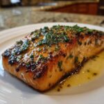 A perfectly cooked fillet of Garlic Butter Salmon with crispy edges, glistening with butter sauce and topped with fresh parsley.