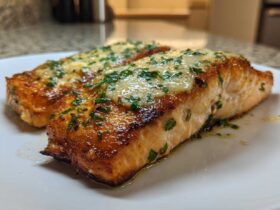 Two perfectly cooked fillets of Garlic Butter Salmon with crispy edges, topped with melted butter sauce and fresh parsley.