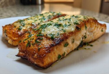 Two perfectly cooked fillets of Garlic Butter Salmon with crispy edges, topped with melted butter sauce and fresh parsley.