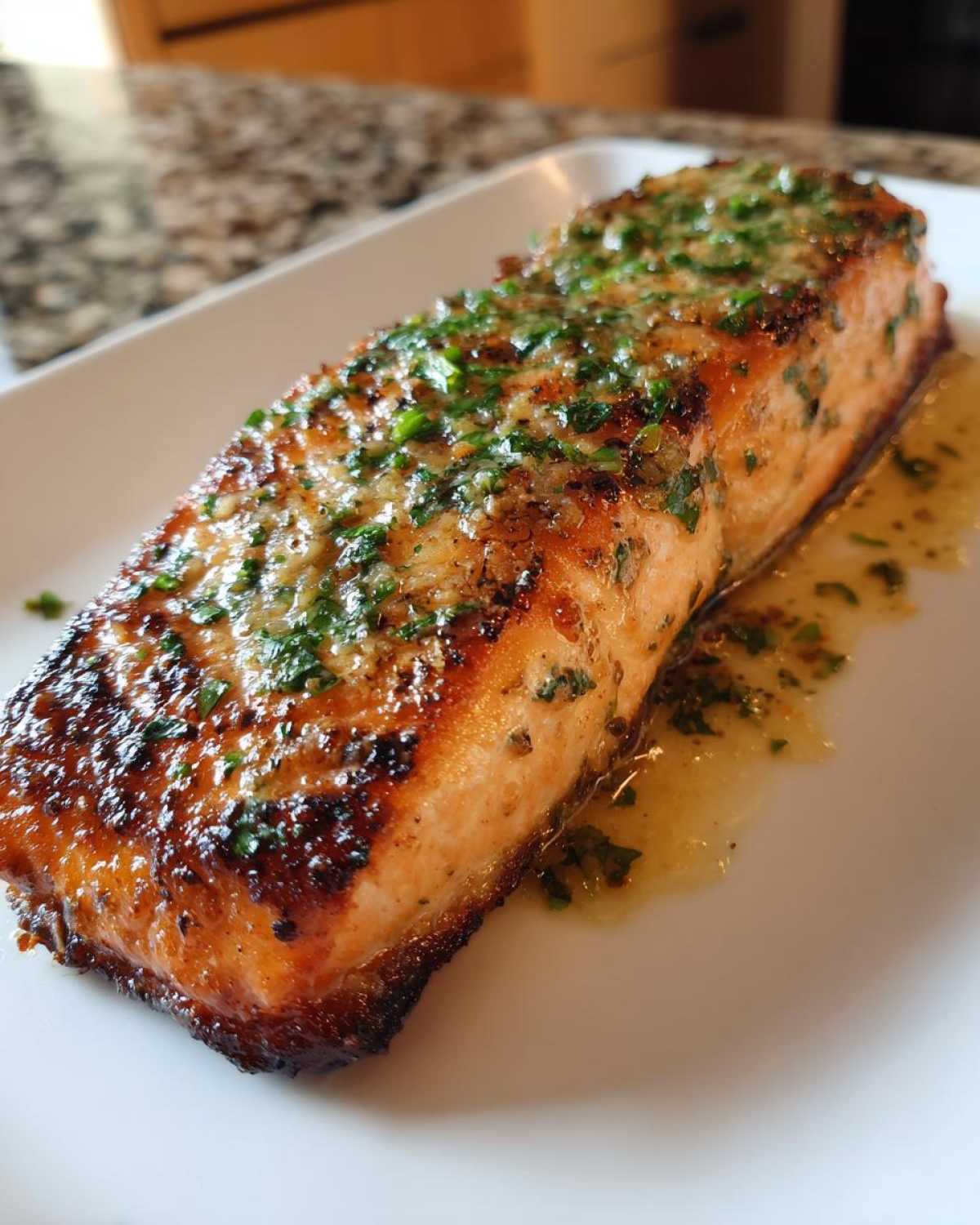 Close-up of a perfectly cooked Garlic Butter Salmon with crispy edges, topped with melted butter and fresh parsley.