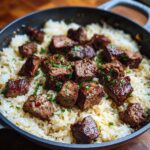 Close-up of tender steak bites served over fluffy rice in a skillet for Garlic Butter Steak and Rice Skillet Dinner.