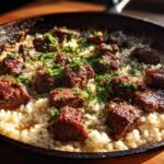 Close-up of Garlic Butter Steak and Rice Skillet Dinner topped with fresh parsley in a dark cast iron pan.