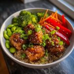 Close-up of a Honey Garlic Chicken Bowl with brown rice, broccoli, edamame, and red peppers.