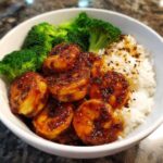 Close-up of a white bowl filled with Honey Garlic Shrimp Bowl Quick Dinner, featuring glazed shrimp, white rice, and steamed broccoli.