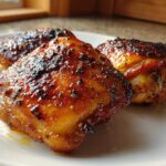 Close-up of three perfectly cooked Honey Soy Chicken Thighs with crispy, caramelized edges on a white plate.
