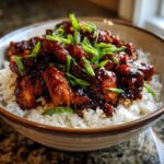 A close-up of a Sticky BBQ Chicken Bowl with Rice, featuring glazed chicken pieces over white rice, topped with fresh green onions.