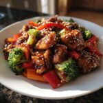 Close-up of Sticky Teriyaki Chicken Stir Fry Quick Meal with broccoli, red peppers, and sesame seeds.